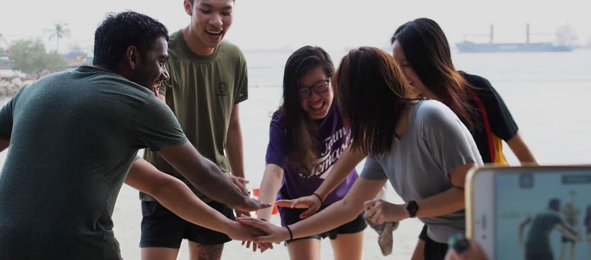 Embry-Riiddle Asia students hands all in on a beach