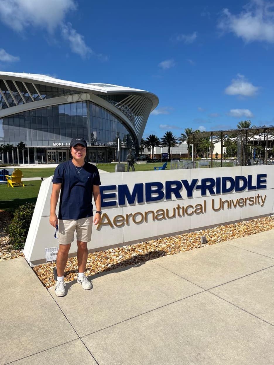 Students stands in front of Embry-Riddle sign.