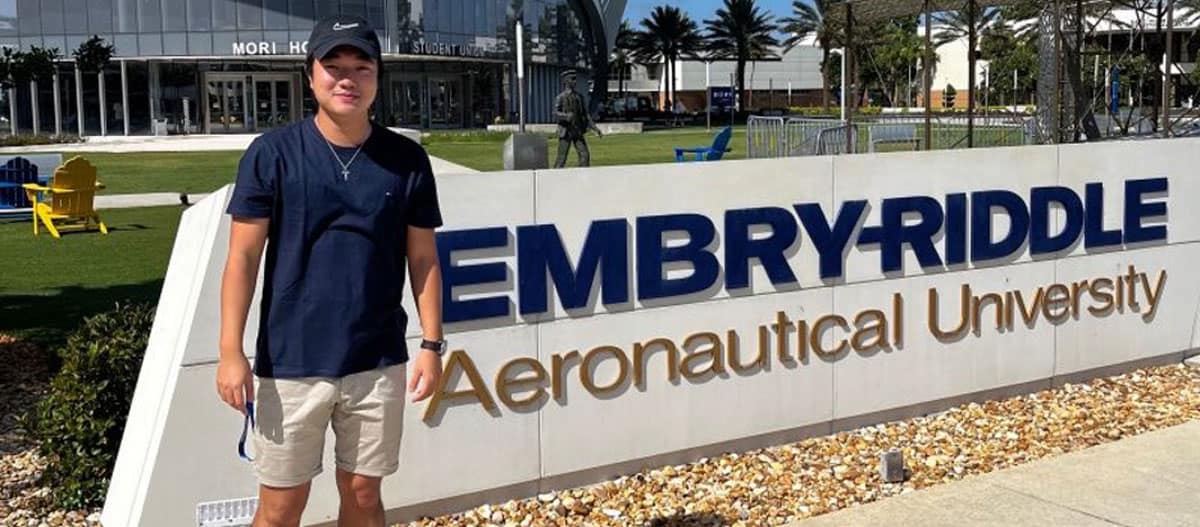 Students stands in front of Embry-Riddle sign.
